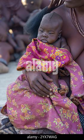 Bébé dans les bras d'une femme Himba, village traditionnel Himba, Kaokoveld, Kunene, Namibie, Afrique Banque D'Images