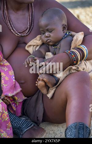 Bébé dans les bras d'une femme Himba, village traditionnel Himba, Kaokoveld, Kunene, Namibie, Afrique Banque D'Images