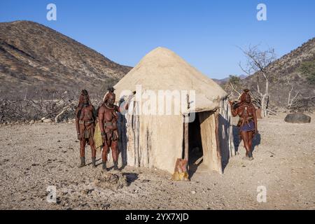 Femme Himba mariée appuyée contre une maison traditionnelle en boue, village traditionnel Himba, Kaokoveld, Kunene, Namibie, Afrique Banque D'Images