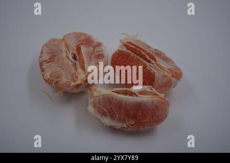 Nourriture saine et saine, beaux fruits frais. La chair rouge du pamplemousse avec de grandes tranches blanches est située sur un fond plastique blanc. Banque D'Images