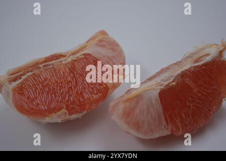 Nourriture saine et saine, beaux fruits frais. La chair rouge du pamplemousse avec de grandes tranches blanches est située sur un fond plastique blanc. Banque D'Images