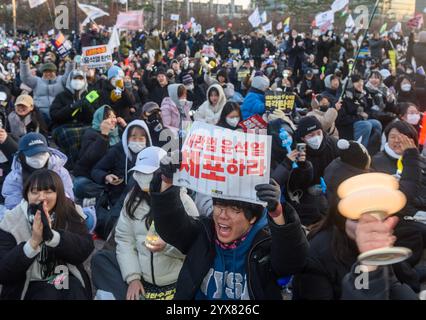 Séoul, Corée du Sud. 14 décembre 2024. Les Sud-Coréens célèbrent après que le parlement a voté la destitution du président Yoon Suk Yeol devant l'Assemblée nationale. L'Assemblée nationale de Corée du Sud a voté pour mettre en accusation le président Yoon Suk Yeol pour son imposition bâclée de la loi martiale, le suspendant de ses fonctions jusqu'à ce que la Cour constitutionnelle décide de le réintégrer ou de le démettre de ses fonctions. Crédit : SOPA images Limited/Alamy Live News Banque D'Images