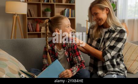 Maman caucasienne heureuse femme parent tressant cheveux curieux petit enfant écolière éducation soins à la maison femme de famille fille mère se détendre preteen Kid Banque D'Images