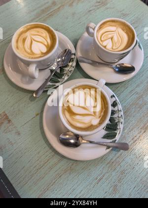 Trois blancs plats dans des tasses, des sauseurs et une cuillère sur une table Banque D'Images