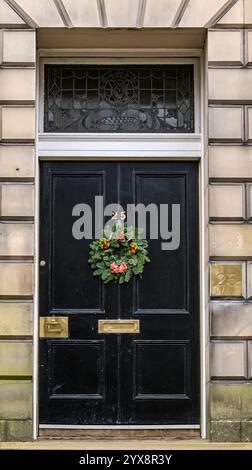 Panneau avant géorgien peint porte noire avec lumière de ventilateur et couronne de Noël, Edinburgh New Town, Écosse, Royaume-Uni Banque D'Images
