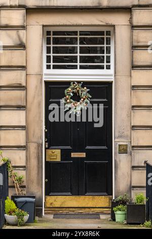 Panneau avant géorgien peint porte noire avec lumière de ventilateur et couronne de Noël, Edinburgh New Town, Écosse, Royaume-Uni Banque D'Images