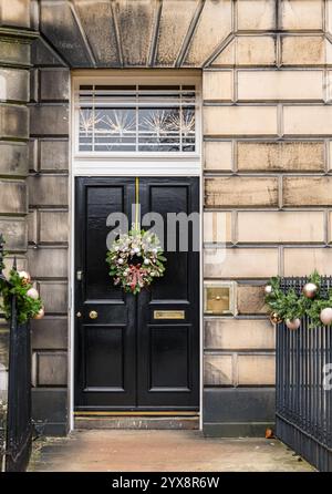 Panneau avant géorgien peint porte noire avec lumière de ventilateur et couronne de Noël, Edinburgh New Town, Écosse, Royaume-Uni Banque D'Images