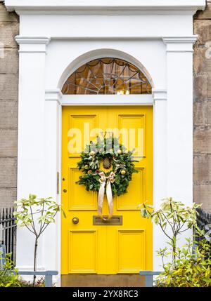 Panneau avant géorgien peint jaune vif porte avec lumière en éventail avec couronne de Noël, Edinburgh New Town, Écosse, Royaume-Uni Banque D'Images