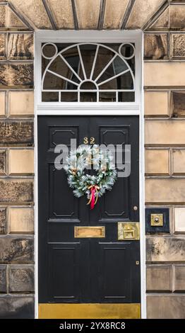 Panneau avant géorgien peint porte noire avec lumière de ventilateur et couronne de Noël, Edinburgh New Town, Écosse, Royaume-Uni Banque D'Images