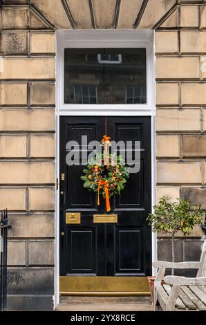 Panneau avant géorgien peint porte noire avec lumière de ventilateur et couronne de Noël, Edinburgh New Town, Écosse, Royaume-Uni Banque D'Images
