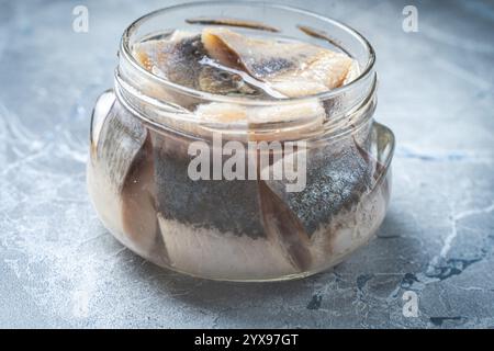 Morceaux de hareng mariné dans un bocal en verre sur une table en marbre gris. Photo de haute qualité Banque D'Images