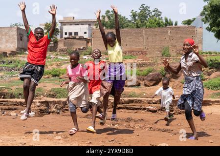 Groupe d'enfants ouest-africains en compétition heureuse les uns avec les autres dans le sol du village. Symbole de bonheur sans possession de richesse Banque D'Images