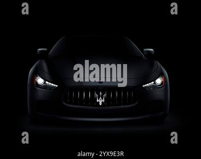Photo spectaculaire d'un sombre 2014 Maserati Ghibli S Q4 Voiture de luxe, vue avant avec phares lumineux isolé sur fond noir Banque D'Images