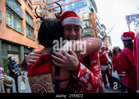 Les participants vêtus de costumes s'embrassent pendant l'événement. Des centaines de fêtards habillés en Père Noël assistent au Santa Con de Londres en 2024. Avec ses origines aux États-Unis, Santa Con est devenu un événement londonien traditionnel d'avant Noël. En commençant par une tournée des pubs deux semaines avant Noël, les Santas défilent à travers Londres, chantant et distribuant des cadeaux à on Lookers. Alors que la grande majorité des participants à Santa Con sont de bonne nature et bien comportés, l'ivresse et la violence ont eu lieu dans le passé. Banque D'Images