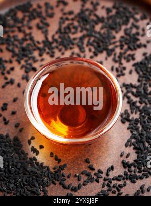 Huile de cumin noir ou de graines de Nigella sativa dans un bol en verre sur fond brun Banque D'Images