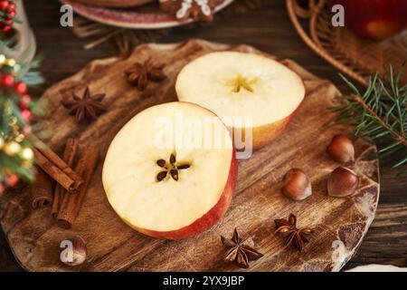 Pomme rouge coupée en deux avec une étoile au milieu avec cannelle, anis étoilé et décoration de Noël Banque D'Images