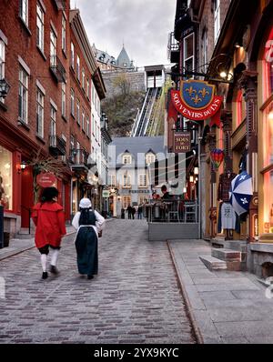 Deux personnes en costumes médiévaux à monter la rue sous le Fort Street dans le vieux Québec avec funiculaire en arrière-plan. Souvenirs du Lys, under the Banque D'Images