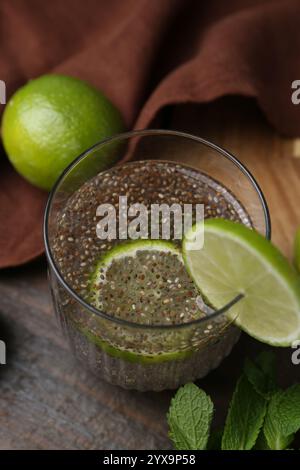 Verre de boisson avec des graines de chia et citron vert sur une table en bois, gros plan Banque D'Images