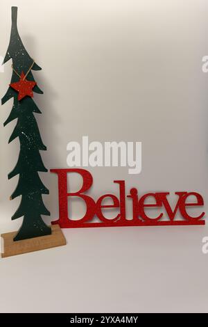 Le mot croire à côté d'un arbre de Noël sculpté avec un fond blanc propre sans couture Banque D'Images