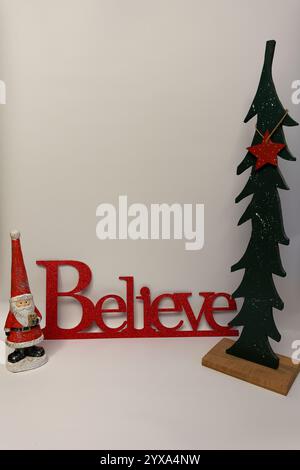 Le mot croire à côté d'un arbre de Noël sculpté avec un fond blanc propre sans couture Banque D'Images