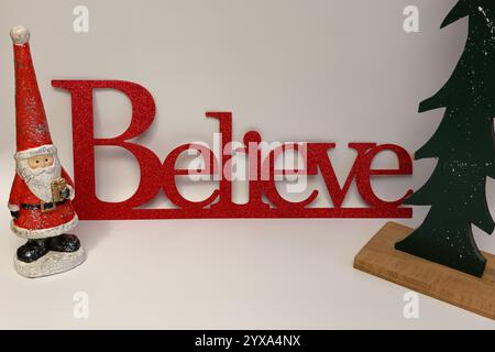 Le mot croire à côté d'un arbre de Noël sculpté avec un fond blanc propre sans couture Banque D'Images