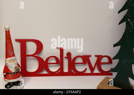 Le mot croire à côté d'un arbre de Noël sculpté avec un fond blanc propre sans couture Banque D'Images