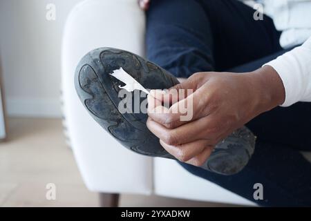 Retrait de la gomme collante de la semelle de chaussure avec les mains rapprochées Banque D'Images
