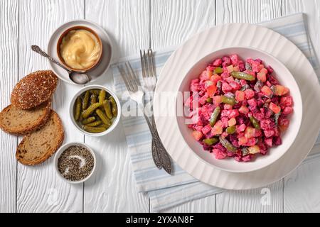 Rosolli, salade de Noël traditionnelle finlandaise dans un bol blanc sur une table en bois blanc avec fourchettes, pain de seigle et vinaigrette maison, vue horizontale Banque D'Images