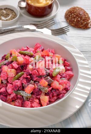 Rosolli, salade traditionnelle finlandaise de Noël festive dans un bol blanc sur une table en bois blanc avec fourchettes, pain de seigle et vinaigrette végétalienne maison, v Banque D'Images