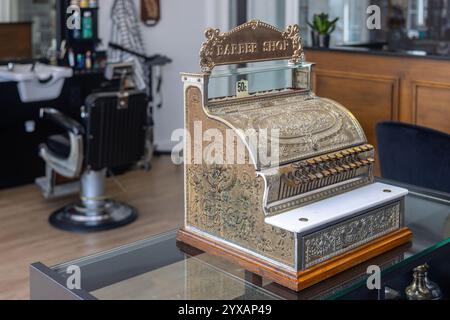 Une caisse enregistreuse vintage ornée exposée dans un salon de coiffure traditionnel, avec des gravures complexes et une étiquette de prix nostalgique de 50 cents. Banque D'Images