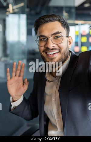 Un homme mûr, un homme d’affaires, s’engage dans un appel vidéo avec un sourire charismatique, créant un environnement accueillant et professionnel. Banque D'Images
