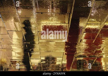 Silhouette dans les rues humides : une nuit pluvieuse dans la ville Banque D'Images