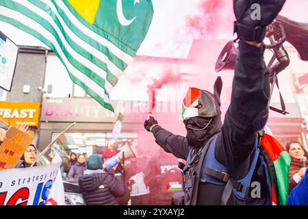 Birmingham, Royaume-Uni. 14 DEC, 2024. Activiste en masque tient une fusée alors qu'une foule de Pro Palestine marchait du parc Handsworth au centre de Birmingham, le groupe, y compris ceux portant des gommages dans le cadre de Healthworkers 4 Palestine chantait et allumait des fusées éclairantes. Des groupes de Liverpool et de Londres se sont joints. Crédit Milo Chandler/Alamy Live News Banque D'Images