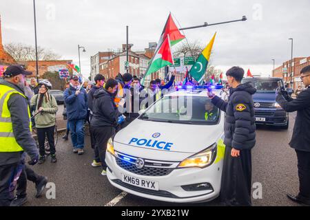 Birmingham, Royaume-Uni. 14 DEC, 2024. La police parle aux manifestants alors qu'une foule de Pro Palestine marchait du parc Handsworth au centre de Birmingham, le groupe, y compris ceux portant des gommages dans le cadre de HealthWorkers 4 Palestine, a chanté et allumé des fusées éclairantes. Des groupes de Liverpool et de Londres se sont joints. Crédit Milo Chandler/Alamy Live News Banque D'Images