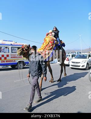 Udaipur, Rajasthan, Inde, 14 décembre 2024 : les touristes montent à dos de chameau près du lac Fateh Sagar par une froide journée d'hiver dans la ville lacustre d'Udaipur. Crédit : Sumit Saraswat / Alamy Live News Banque D'Images
