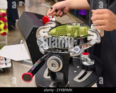 Cordes une raquette de badminton sur une machine à cordes de raquettes. Banque D'Images