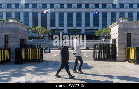 Séoul, Corée du Sud. 15 décembre 2024. Les gens passent devant la Cour constitutionnelle de Séoul. Tous les yeux sont maintenant tournés vers la Cour constitutionnelle de Corée du Sud, qui détient la décision finale sur la destitution du président Yoon Suk Yeol, après que le parlement a voté le 14 décembre pour l'évincer à la suite de son invocation de la loi martiale le 3 décembre qui a déclenché des troubles politiques sans précédent. Crédit : SOPA images Limited/Alamy Live News Banque D'Images