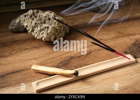 Support avec bâtons d'encens fumants, Palo Santo et pierres sur table en bois Banque D'Images