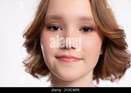 Une jeune femme souriante avec de courts cheveux ondulés posant magnifiquement sur un fond blanc Banque D'Images