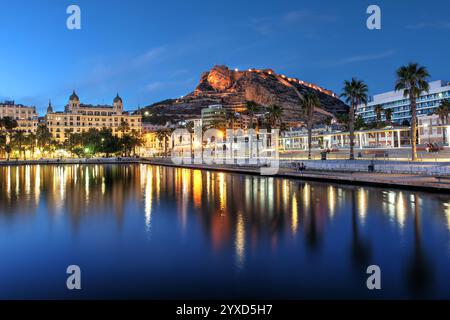 Scène de coucher de soleil dans le port d'Alicante, Espagne avec le château Santa Barbara qui menace la ville. Banque D'Images