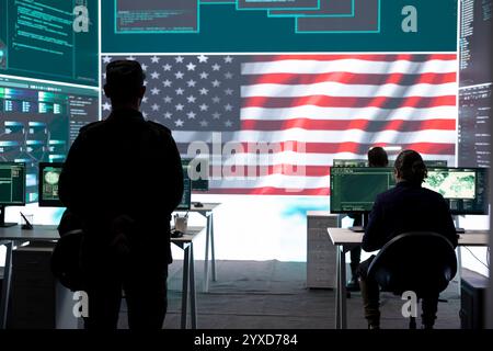 Homme militaire AMÉRICAIN supervisant l'activité de détection des menaces dans le bureau de haute technologie, examinant les données top secrètes sur grand écran. Soldats gouvernementaux gérant la guerre hybride, prévention des cyberattaques. Banque D'Images