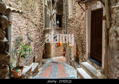 Une étroite ruelle pavée à flanc de colline serpentant le village médiéval historique de Dolceacqua, en Italie, dans la région de Ligurie. Banque D'Images