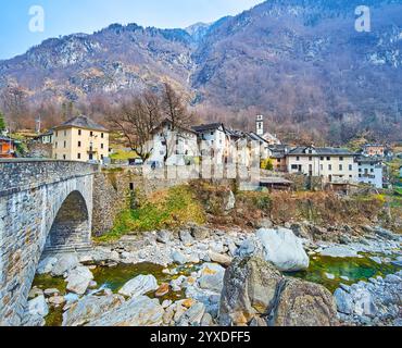 Le vieux pont de pierre sur la rivière Maggia et la montagne médiévale Prato Sornico village contre les Alpes rocheuses, Val Lavizzara, Vallemaggia, Ticin Banque D'Images