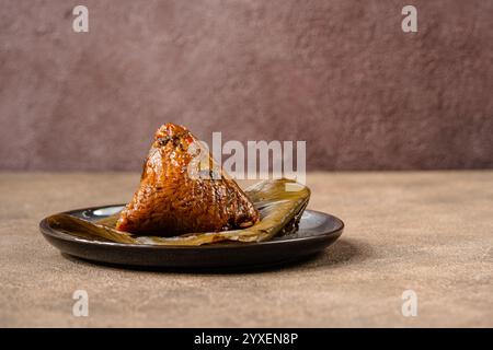 Le zongzi est un aliment chinois traditionnel fait de riz gluant farci avec différentes garnitures et enveloppé dans du roseau de bambou, ou d'autres grandes feuilles plates. Th Banque D'Images