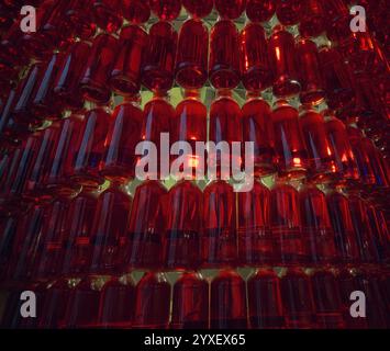 Arrangement abstrait de bouteilles en verre rouge avec des reflets de lumière créant un effet visuel vibrant Banque D'Images