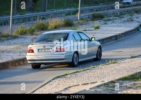 bmw 520d argenté conduisant sur une route asphaltée près d'une autoroute, mettant en valeur les thèmes du transport et de l'automobile Banque D'Images