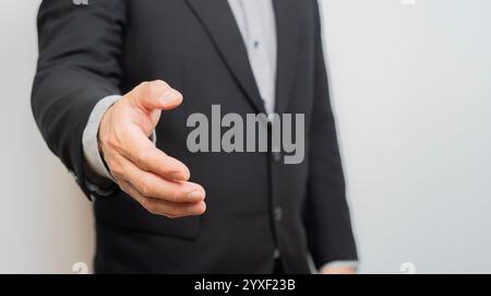 Image recadrée de l'homme d'affaires donnant sa main pour poignée de main à partenaire. Mise au point sélective, espace de copie. Banque D'Images