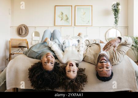 Une famille profite d’un moment joyeux ensemble à la maison en riant et en jouant sur un lit, mettant en valeur un lien familial positif et le bonheur. Banque D'Images