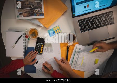 Deux personnes travaillent sur un projet ensemble, avec un ordinateur portable, couple organisant des documents de crédit. Nouveau concept de maison. Banque D'Images