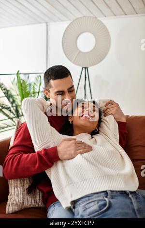 Un couple se détend ensemble dans un loft élégant, appréciant la chaleur et le rire de l'autre. Banque D'Images